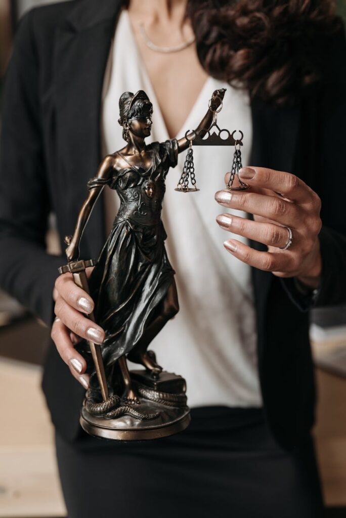 pexels-photo-8111818-8111818 Close-up of Lady Justice statuette held by a lawyer, symbolizing law and justice.